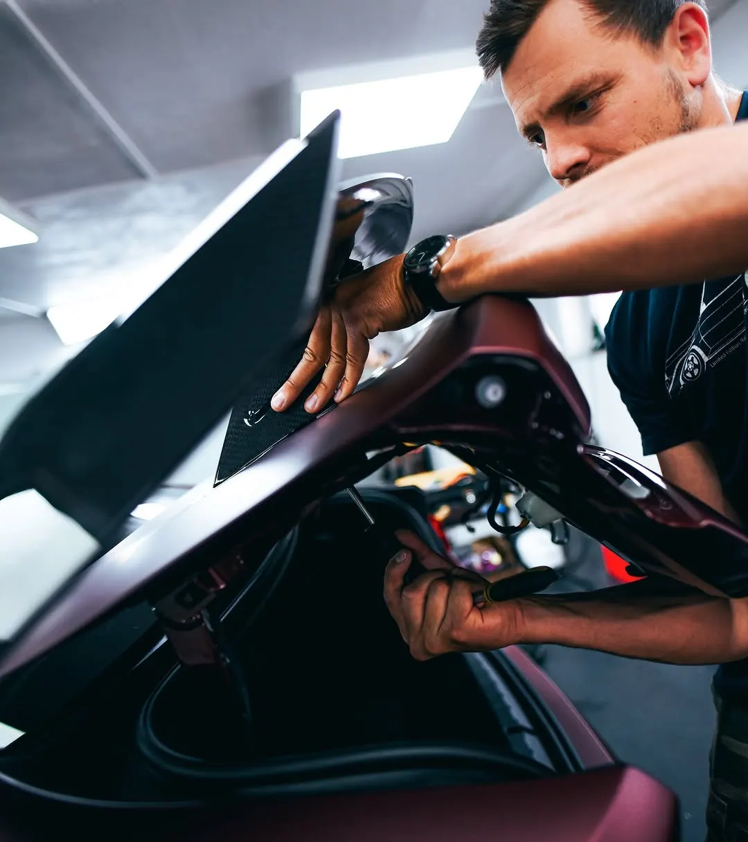 Technik usazuje zadní křídlo na víko kufru vozu